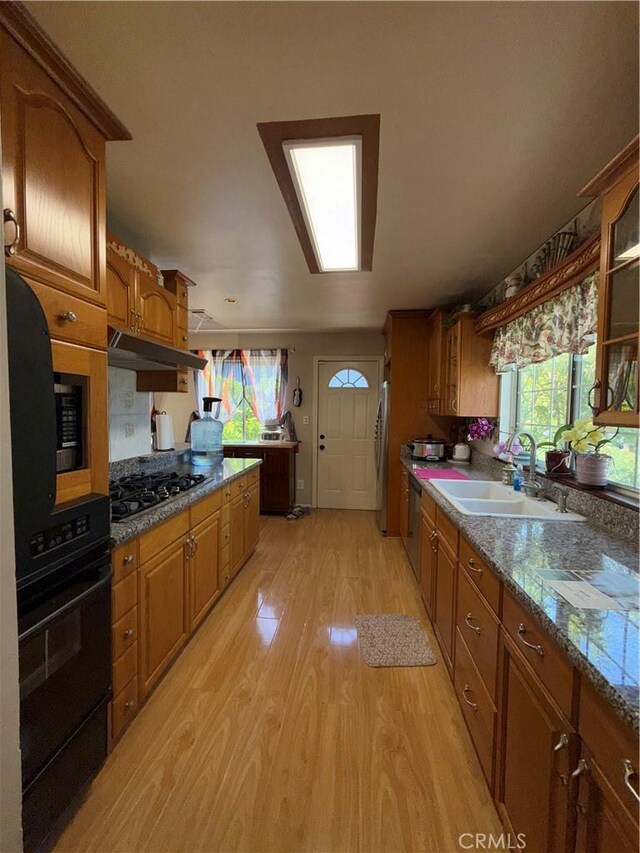 1711 S Washington Ave, Glendora, CA 91740 - kitchen featuring appliances with stainless steel finishes, brown cabinetry, light wood-type flooring, under cabinet range hood, and glass insert cabinets