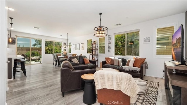 living area featuring light wood finished floors, a chandelier, and a wealth of natural light