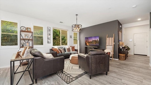 living room featuring baseboards, plenty of natural light, light wood finished floors, and a notable chandelier