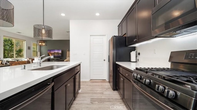 kitchen featuring a sink, gas stove, light wood finished floors, light countertops, and dishwasher