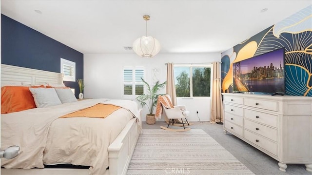 bedroom featuring visible vents, multiple windows, and light carpet