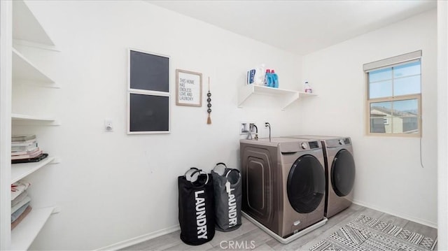 clothes washing area featuring laundry area, baseboards, washing machine and dryer, and wood finished floors