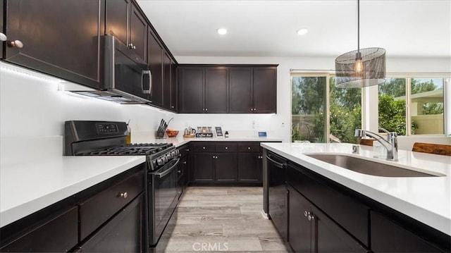kitchen featuring decorative light fixtures, a sink, light countertops, black appliances, and recessed lighting