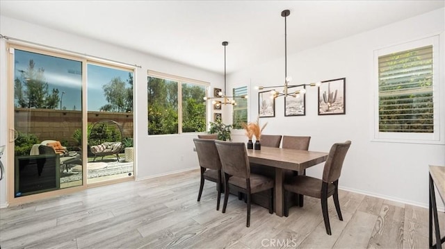 dining space featuring light wood-type flooring, baseboards, and a notable chandelier