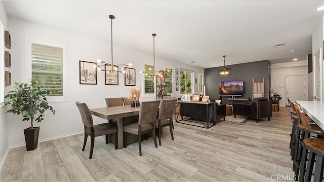 dining room with a notable chandelier, visible vents, and light wood-type flooring
