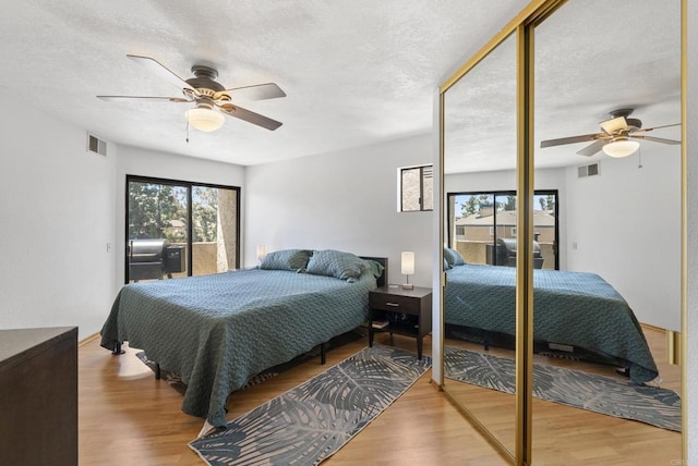 bedroom with wood finished floors, a textured ceiling, a ceiling fan, and access to exterior
