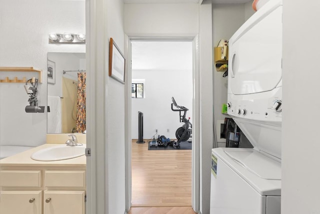 laundry room with stacked washing machine and dryer and light wood finished floors