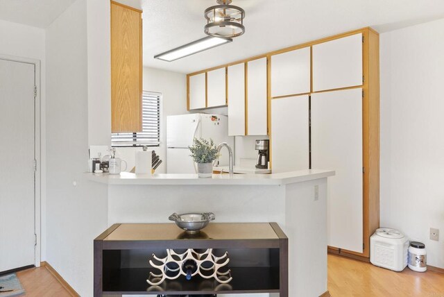 9725 Mesa Springs Way Unit 176, San Diego, CA 92126 - kitchen featuring freestanding refrigerator, light countertops, light wood-style floors, a peninsula, and white cabinets