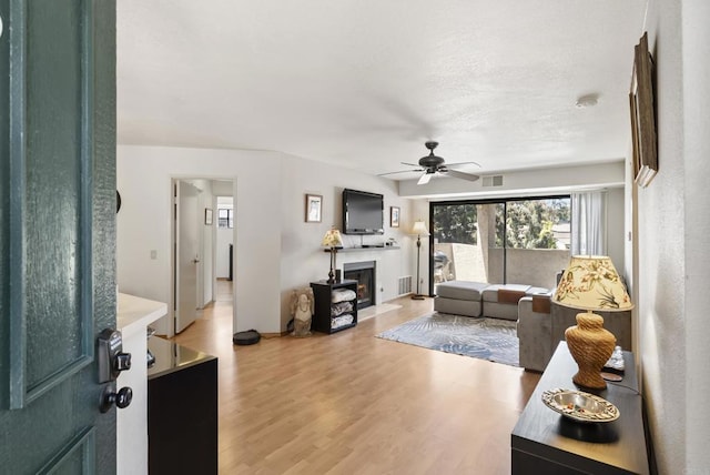 9725 Mesa Springs Way Unit 176, San Diego, CA 92126 - living room with light wood finished floors, a fireplace with flush hearth, and a ceiling fan