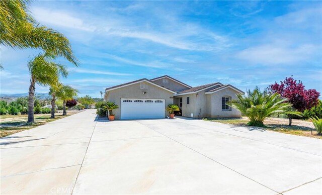 single story home with an attached garage, driveway, and stucco siding