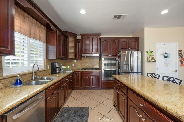kitchen featuring a sink, stainless steel appliances, backsplash, under cabinet range hood, and visible vents