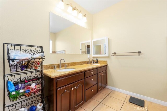 full bathroom with baseboards, a sink, tile patterned floors, and double vanity
