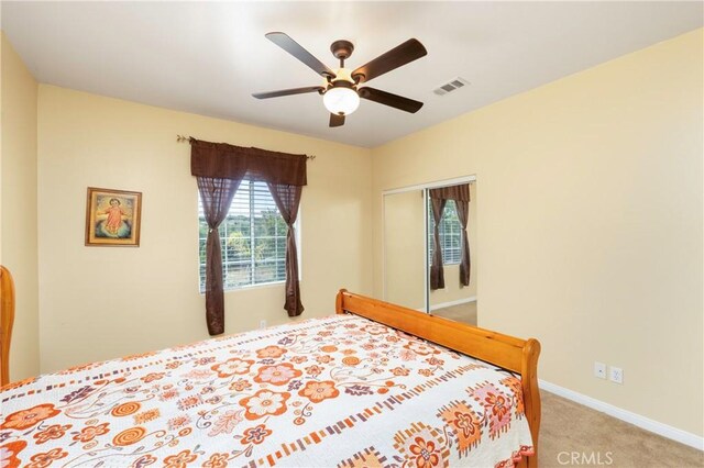 carpeted bedroom with a ceiling fan, baseboards, visible vents, and a closet