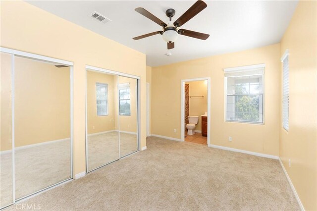 unfurnished bedroom with two closets, visible vents, and carpet