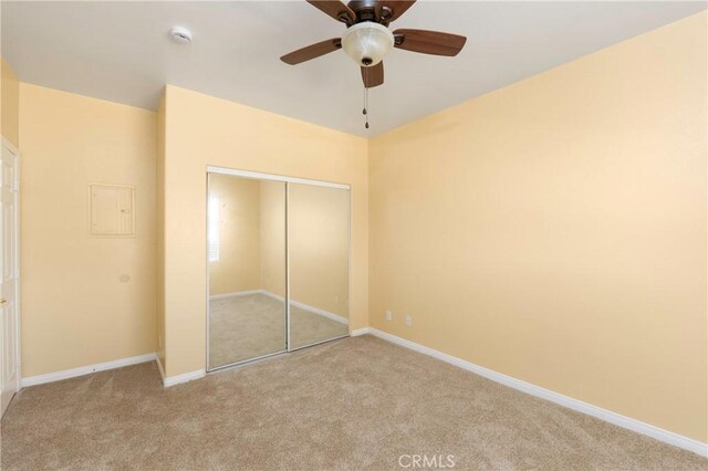 unfurnished bedroom featuring a closet, carpet flooring, baseboards, and ceiling fan