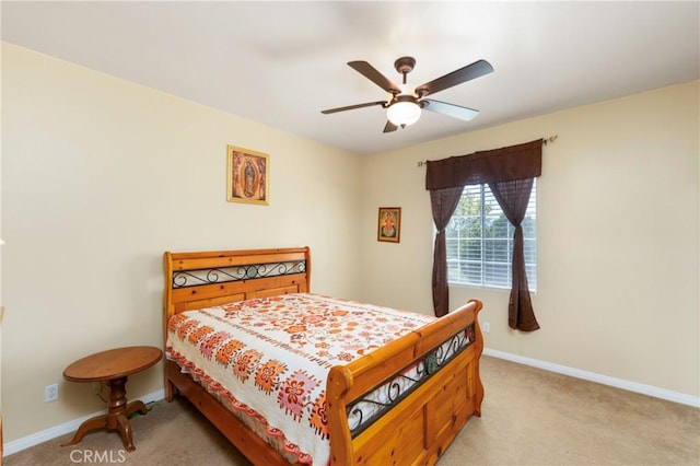 bedroom featuring baseboards, light colored carpet, and ceiling fan