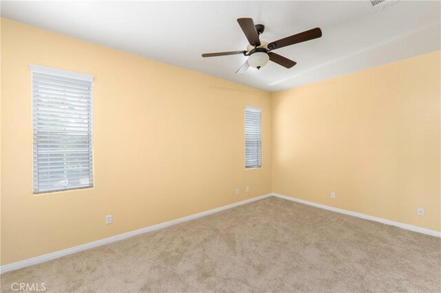 empty room featuring a healthy amount of sunlight, baseboards, carpet, and a ceiling fan