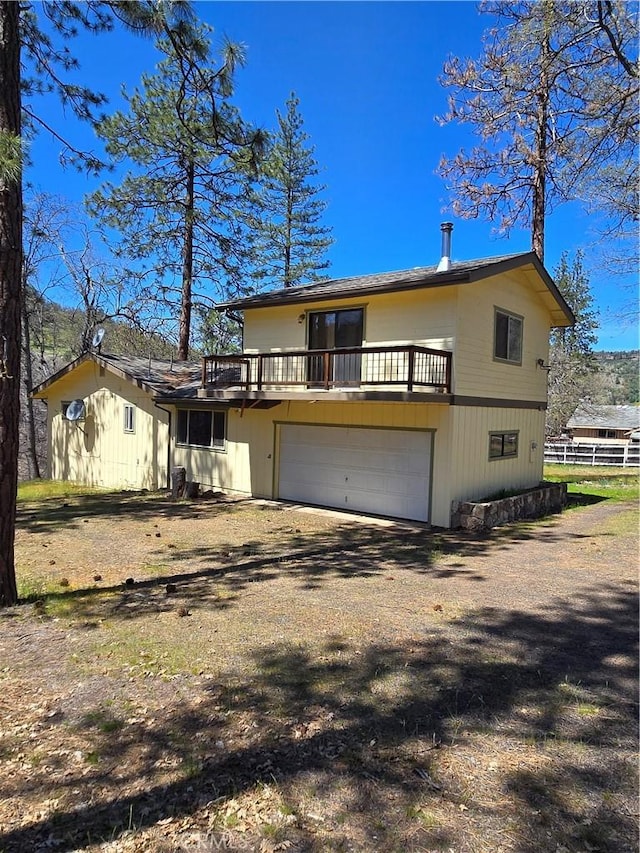 front facade featuring a garage, dirt driveway, and fence