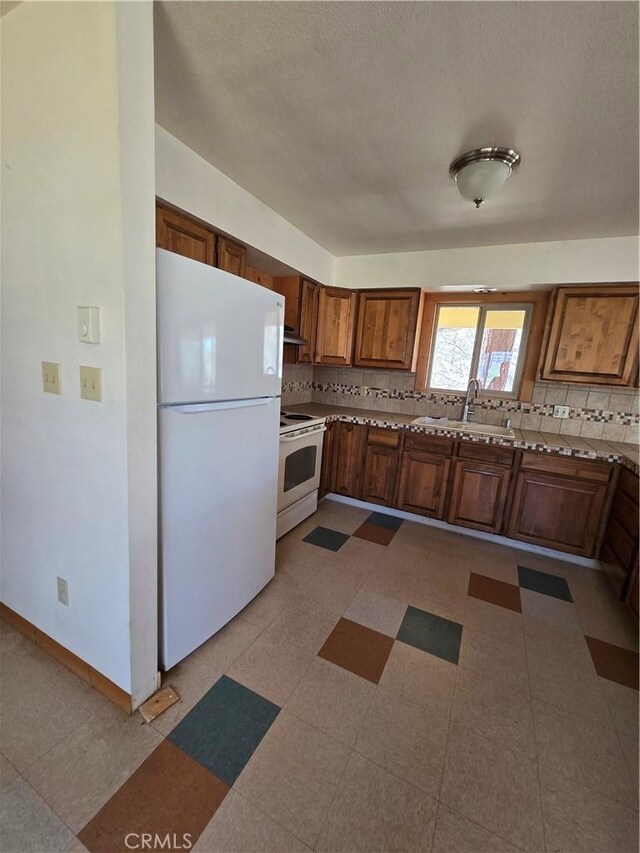 16631 Patricia Ave, Montague, CA 96064 - kitchen with white appliances, baseboards, a sink, and tasteful backsplash
