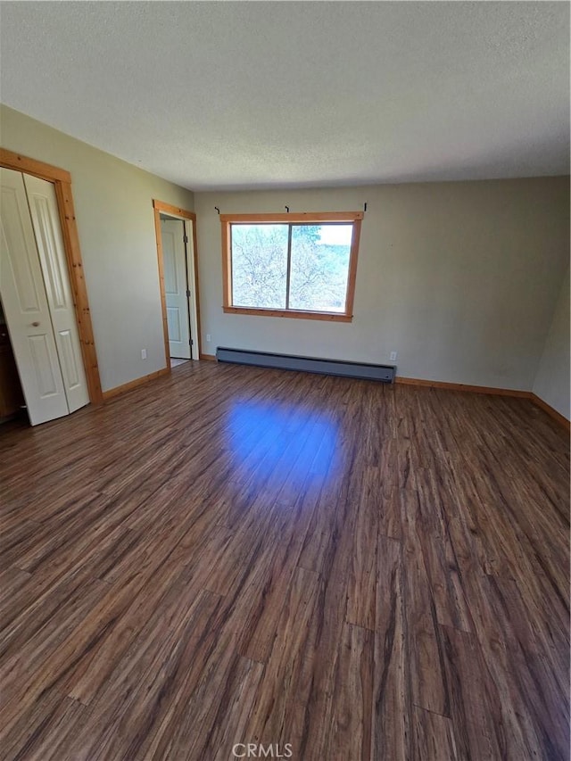 spare room with baseboards, a baseboard radiator, dark wood-style floors, and a textured ceiling