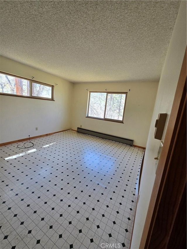 unfurnished room with plenty of natural light, a textured ceiling, baseboards, and baseboard heating