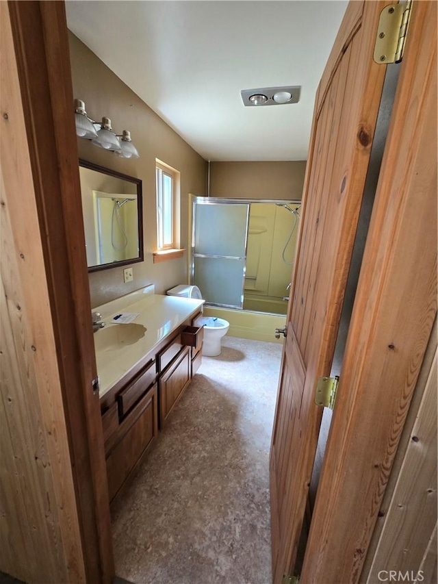 full bath with toilet, bath / shower combo with glass door, and vanity