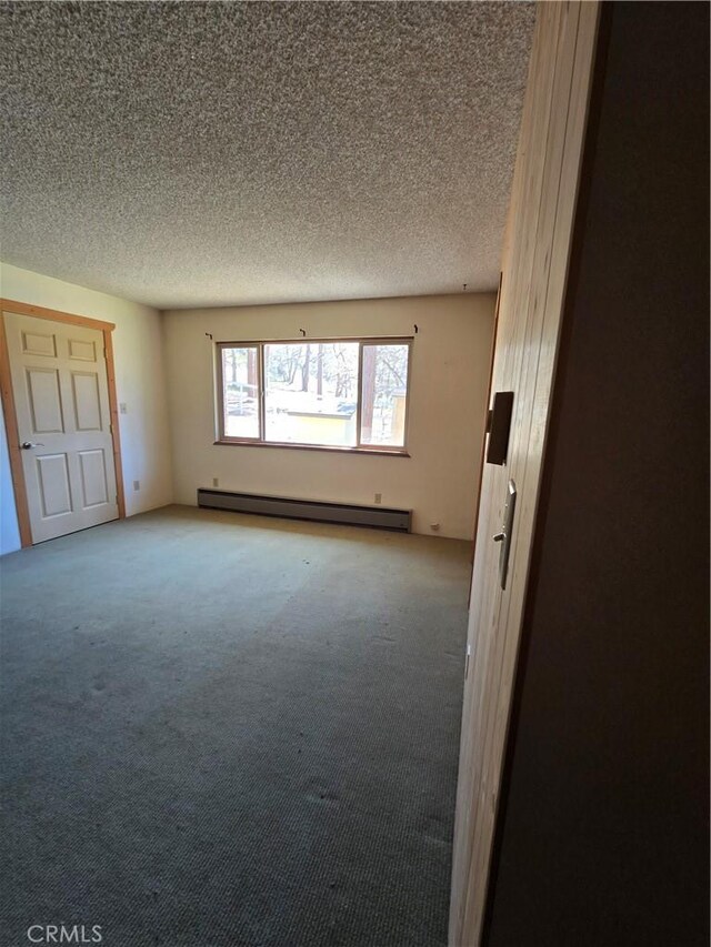 16631 Patricia Ave, Montague, CA 96064 - empty room with light carpet, a baseboard heating unit, and a textured ceiling