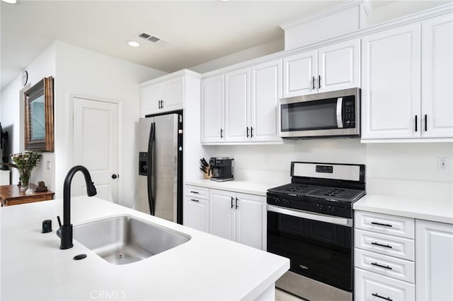 kitchen featuring appliances with stainless steel finishes, a sink, white cabinetry, light countertops, and recessed lighting
