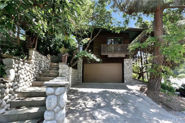 2310 Las Palomas Dr, La Habra Heights, CA 90631 - obstructed view of property with stone siding, concrete driveway, an attached garage, a balcony, and stairway