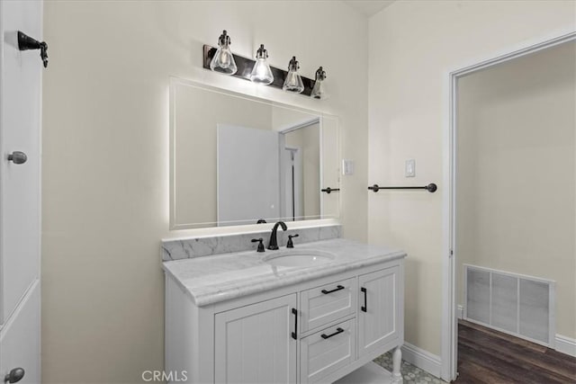 bathroom featuring baseboards, vanity, wood finished floors, and visible vents