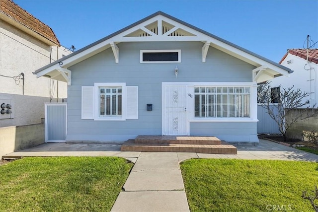 bungalow-style home featuring a front lawn and fence