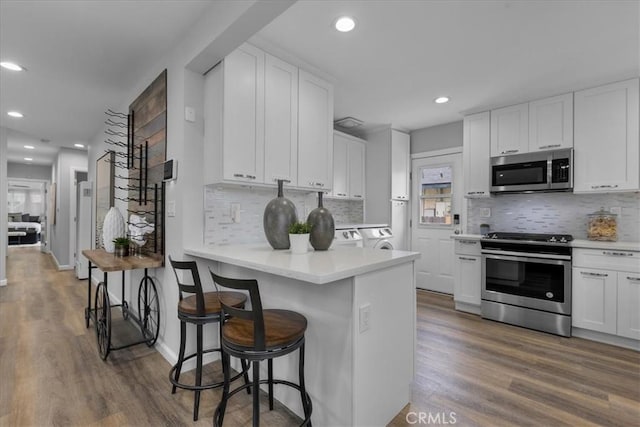 4612 W 161st St, Lawndale, CA 90260 - kitchen featuring appliances with stainless steel finishes, white cabinets, recessed lighting, wood finished floors, and backsplash