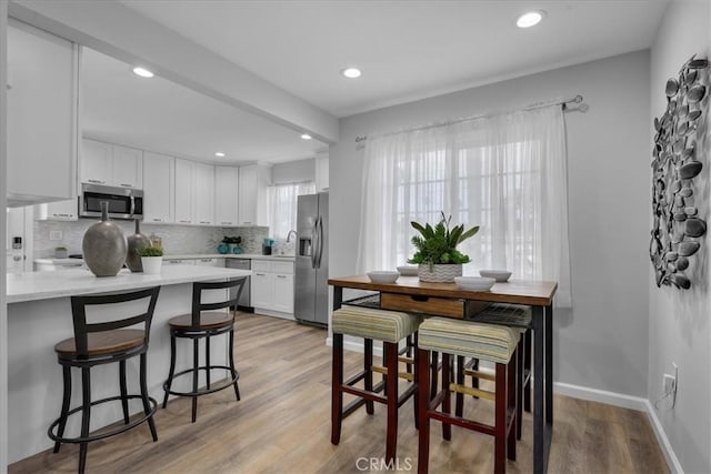 4612 W 161st St, Lawndale, CA 90260 - kitchen with stainless steel appliances, light countertops, white cabinets, light wood-type flooring, and tasteful backsplash