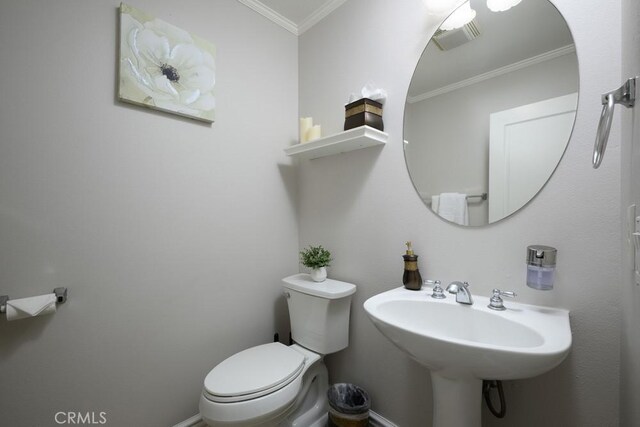 half bathroom featuring toilet, baseboards, ornamental molding, and a sink