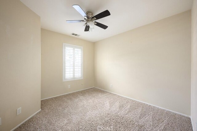 empty room with baseboards, visible vents, carpet flooring, and ceiling fan