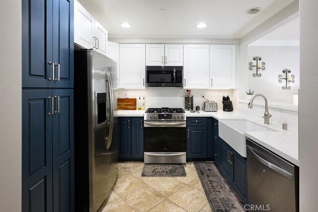 kitchen featuring white cabinets, a sink, blue cabinetry, light countertops, and appliances with stainless steel finishes