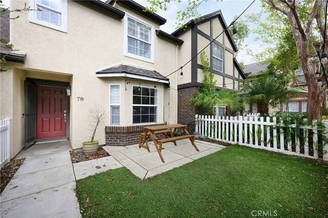back of property featuring stucco siding, fence, a yard, and brick siding