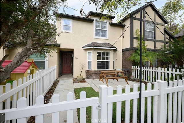 view of front of property featuring stucco siding, brick siding, and a fenced front yard