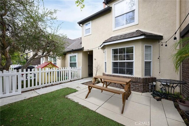 rear view of property with a patio, fence, and stucco siding