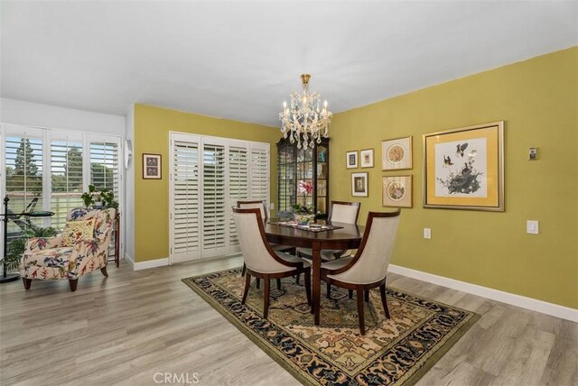 dining room with baseboards, a chandelier, and light wood-style floors