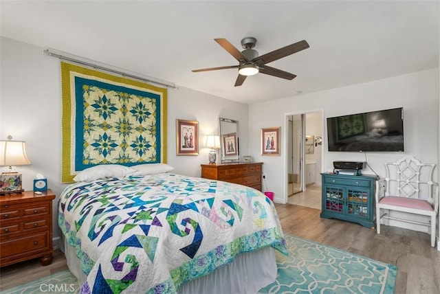 bedroom with ensuite bath, a ceiling fan, and wood finished floors