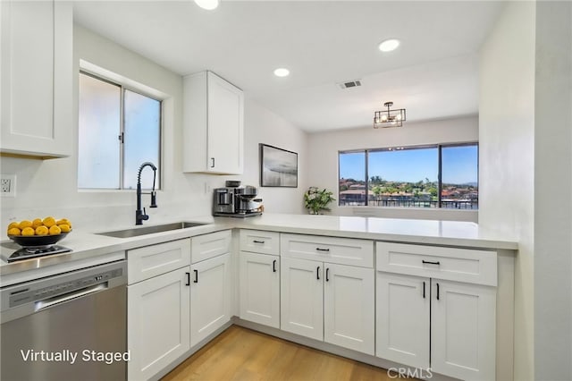 24319 Canyon Lake Dr Unit 10, Canyon Lake, CA 92587 - kitchen with light countertops, visible vents, stainless steel dishwasher, a sink, and white cabinetry