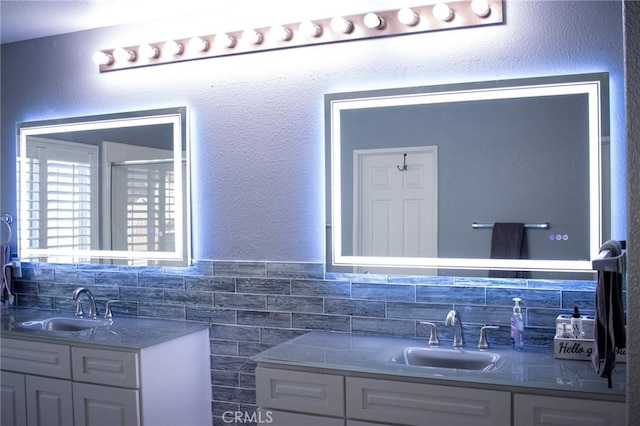 full bath with a textured wall, two vanities, and a sink