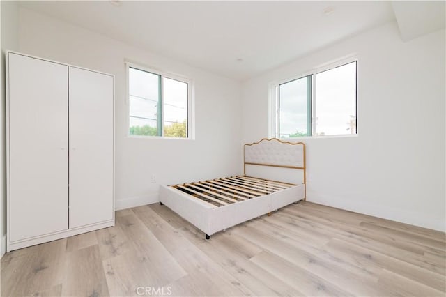 1598 W 36th St, Los Angeles, CA 90018 - unfurnished bedroom featuring a closet, light wood-type flooring, and baseboards