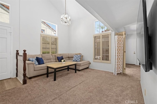 living room featuring carpet floors, high vaulted ceiling, and a chandelier