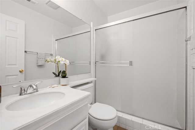 bathroom with vanity, a shower stall, and toilet