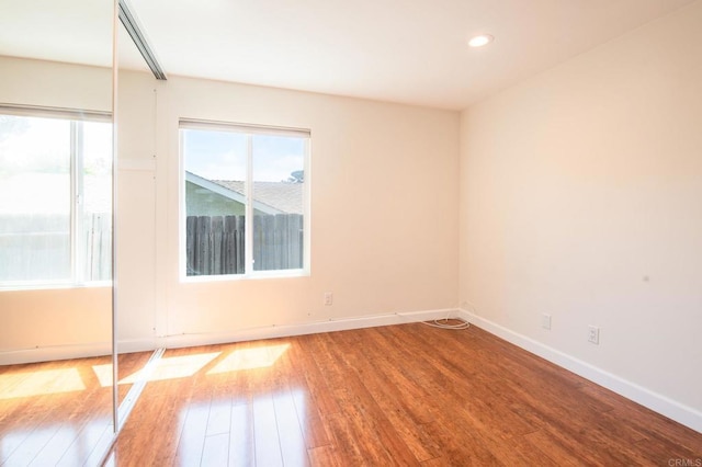 unfurnished room with plenty of natural light, hardwood / wood-style flooring, baseboards, and recessed lighting