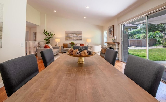 dining room featuring wood finished floors, vaulted ceiling, recessed lighting, and a fireplace