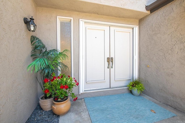 property entrance featuring stucco siding and french doors