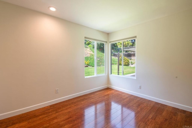 empty room featuring baseboards, hardwood / wood-style flooring, and recessed lighting